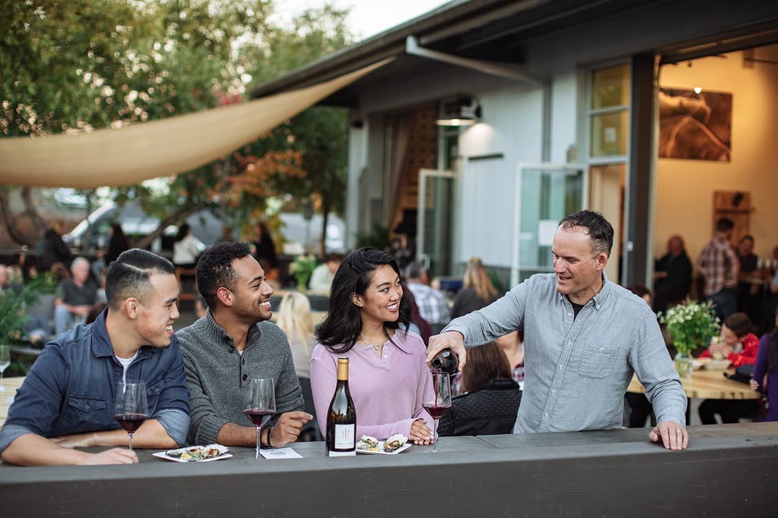 A Region host pours red wine for guests at the outdoor bar